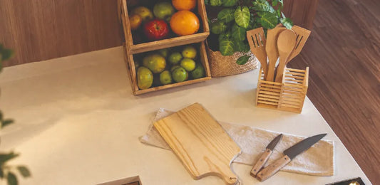 Utensilios de cocina de madera: tabla de picar, cucharas y espátulas en escurridor, cuchillos y frutero sobre la encimera